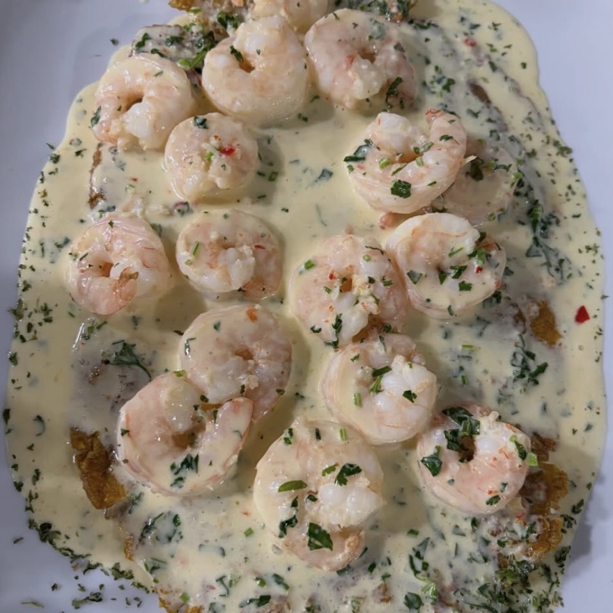 Patacón topped with garlic buttered prawns and house sauce